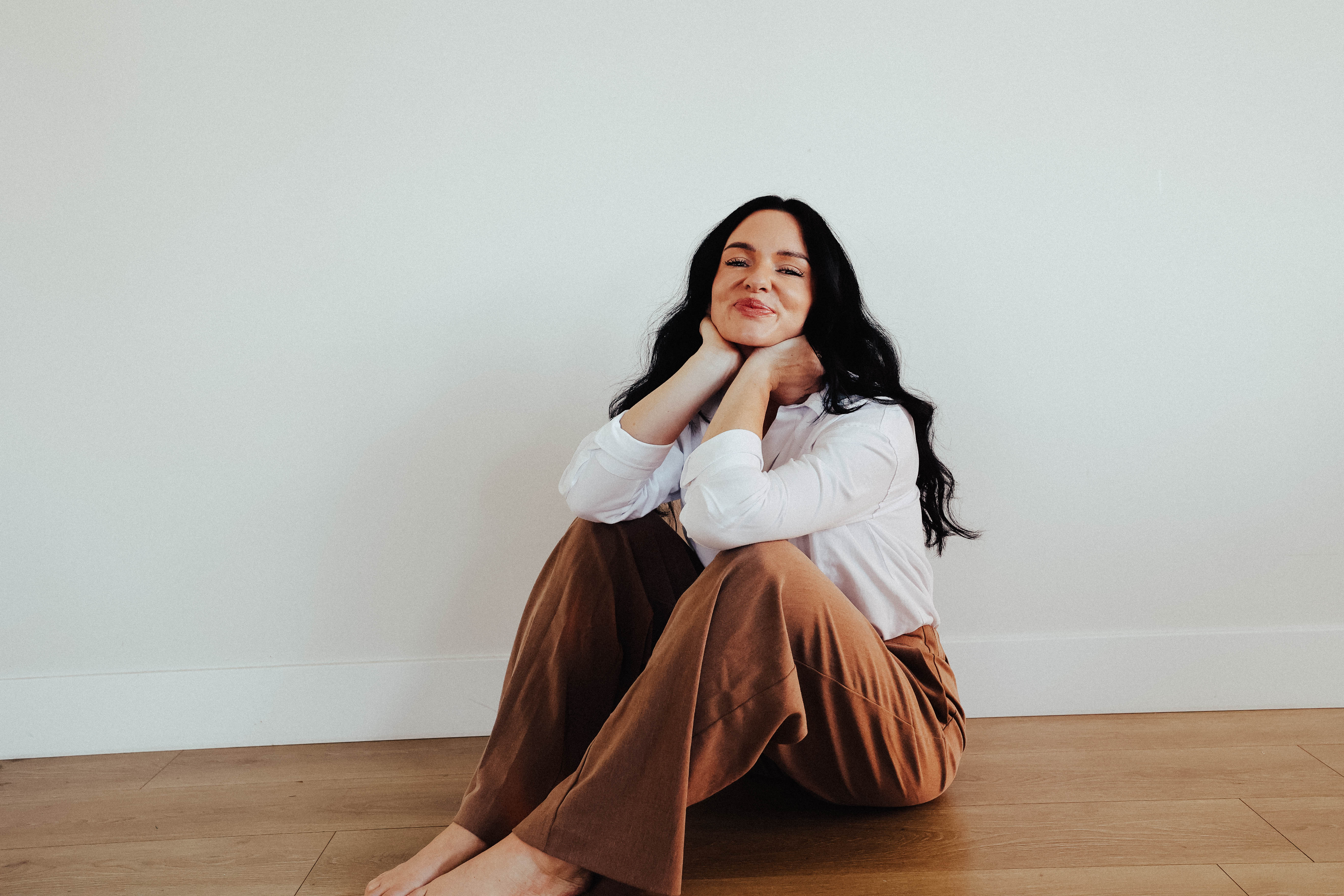 Nikki sitting casually on wooden floor, smiling warmly